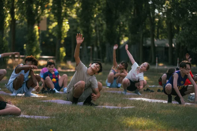 Groep jongeren doet samen een opwarming in het park tijdens IMPACT [Camp]