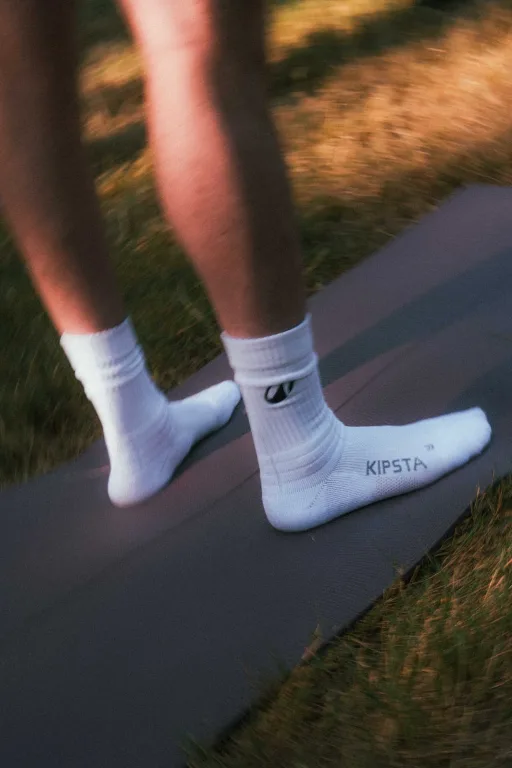 Deelnemer in sportsokken op een yogamat in het gras