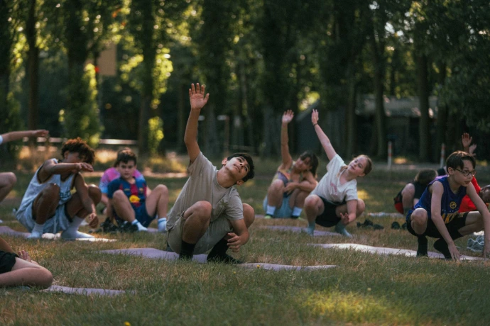 Jongeren doen samen een opwarming in het park tijdens IMPACT [Camp]